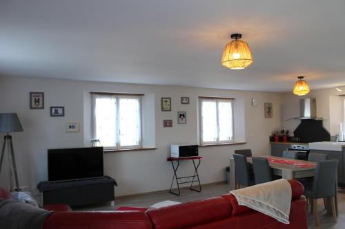 ein Wohnzimmer mit einem roten Sofa und einer Küche in der Unterkunft Gites aux deux Hameaux 2 in Saint-Pierre-Bois