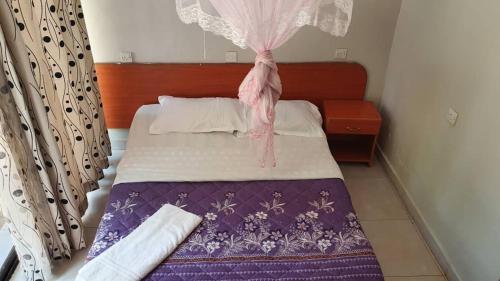 1 dormitorio con 1 cama con manta morada y blanca en Arise Africa International Christian Guesthouse, en Jinja