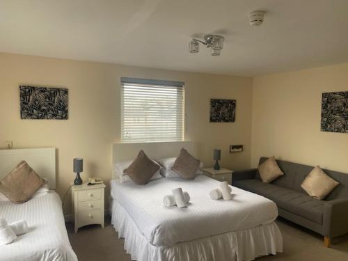 a bedroom with two beds and a couch at Runnymede Court Hotel in Saint Helier Jersey