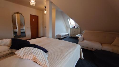 a bedroom with a bed and a couch and a mirror at Guesthouse Četri Vēji in Turkalne