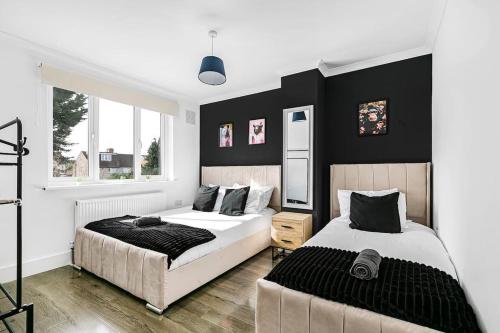 2 camas en un dormitorio con paredes blancas y negras en Luxury Large House With Games Room Sleeps Up to 12 en Feltham