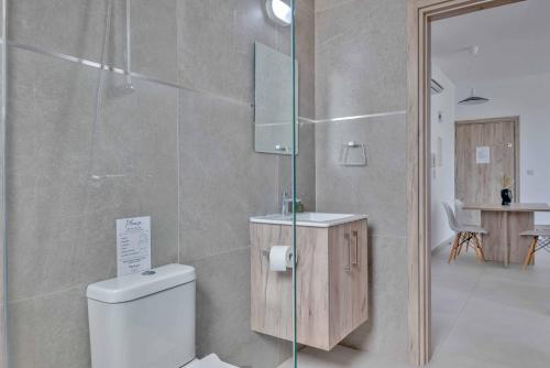 a bathroom with a toilet and a glass shower at Phaedrus Living: City Center Residences Emerald in Nicosia