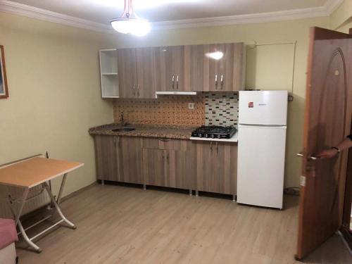 eine Küche mit Holzschränken und einem weißen Kühlschrank in der Unterkunft Ortadoğu apart otel in Ağrı