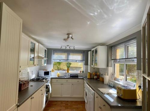 une cuisine avec des armoires blanches et des appareils électroménagers blancs dans l'établissement Honey Cottage, à Pembrokeshire