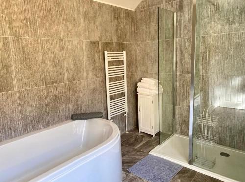 une salle de bain avec baignoire et douche en verre dans l'établissement Honey Cottage, à Pembrokeshire
