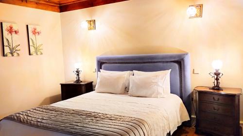a bedroom with a blue bed with two night stands at Quinta do Burgo - Nature Hotel in Amares