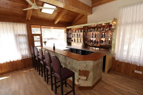 un bar en una habitación con un montón de sillas en Ezzenza Swarg by Beas Golf Resort - Devlok Manali, en Baragrān