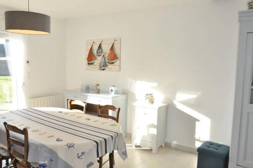 una sala da pranzo bianca con tavolo e sedie di Belle maison 3 etoiles dans la station touristique de Trebeurden à 1km de la mer - Réf 670 a Trébeurden