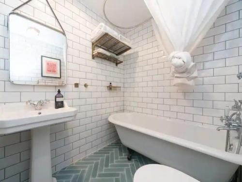 Baño blanco con bañera y lavamanos en Stunning flat Richmond Bridge Pass The Keys, en Twickenham
