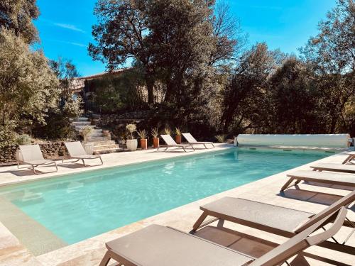 a swimming pool with chaises and lounge chairs in a yard at Hôtel La Bastide de Vaison in Vaison-la-Romaine