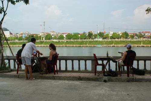 a group of people sitting at a table by the water at Xuan Hoa Hotel in Ninh Binh