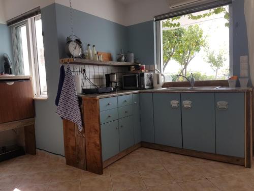 a kitchen with blue cabinets and a window at B&B Hestia's Hideaway in Kalívia Thorikoú