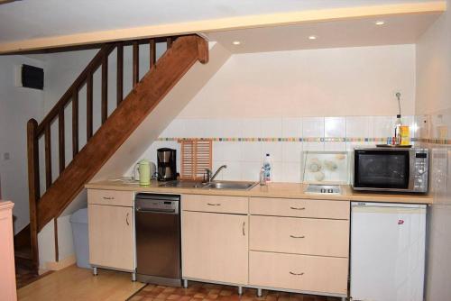 une cuisine avec un évier et un micro-ondes dans l'établissement Maison bretonne avec une jolie cour fermée et fleurie avec WIFI à TREBEURDEN - Réf 679, à Trébeurden