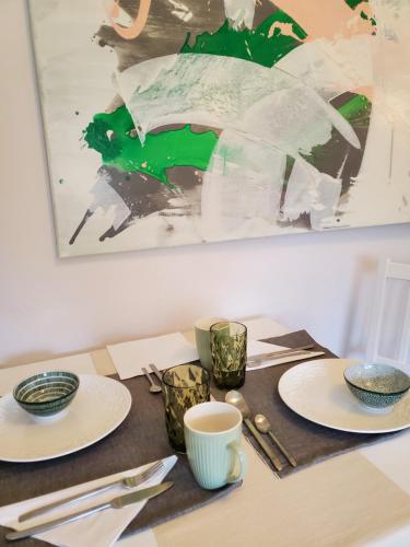 a table with plates and cups and a painting at Privatpension Waldbröl in Waldbröl