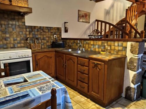 une cuisine avec un évier et une cuisinière dans l'établissement Maison bretonne à 300m de la mer avec cour et jardin clos à PLEUMEUR-BODOU - Réf 693, à Pleumeur-Bodou