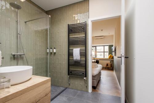 ein Bad mit einem Waschbecken und einer Glasdusche in der Unterkunft Badhuis Hotel in Utrecht