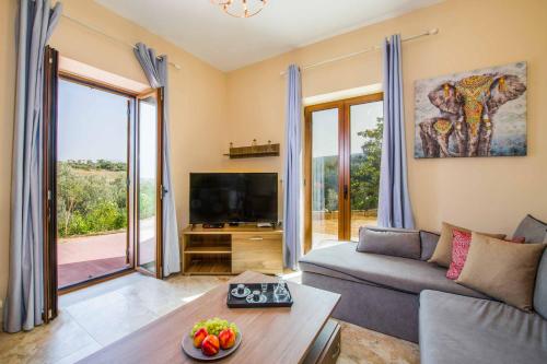 a living room with a couch and a tv at Villa Erato Klio in Kiriánna