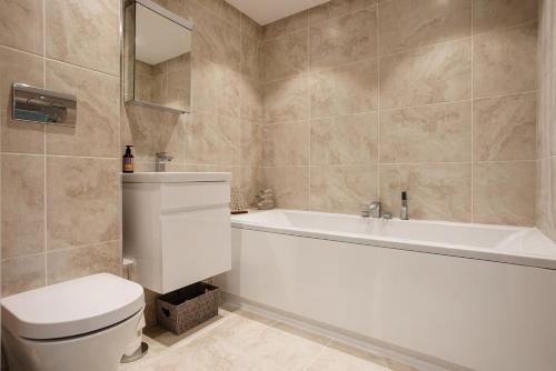 a bathroom with a tub and a toilet and a sink at Blue Horizon in Sandown
