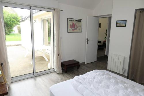 a bedroom with a bed and a sliding glass door at Maison neuve de plain-pied à 100m de la mer et 200m du Coz-Pors à TREGASTEL - Ref 71 in Trégastel