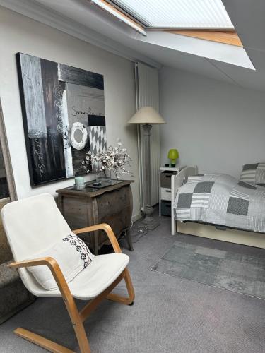 a bedroom with a bed and a white chair at cosy loft in town house in Paris