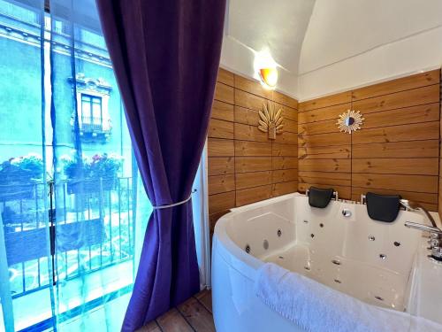 eine Badewanne in einem Zimmer mit einem großen Fenster in der Unterkunft CANTU' SUITE in Catania