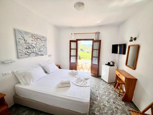 a bedroom with a large white bed and a table at Nicolas Studios in Skala