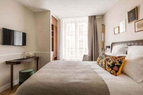 a hotel room with a large bed and a desk at Hôtel Chamar in Paris