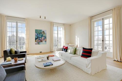 ein Wohnzimmer mit weißen Möbeln und großen Fenstern in der Unterkunft Pick A Flat's Apartment in Invalides - Rue de Constantine in Paris