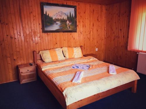 a bedroom with a bed with a picture on the wall at Casa Iulia si Bogdan in Bran