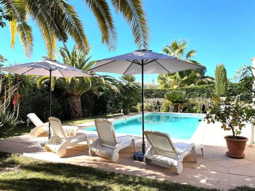 un groupe de chaises et de parasols à côté d'une piscine dans l'établissement Maison cosy en bordure du golf., à Saint-Raphaël