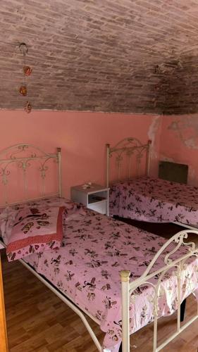 two beds in a bedroom with pink walls at Casa Manzo in Montemurro