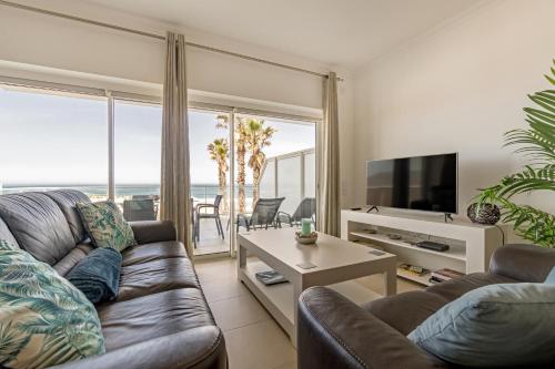 a living room with a couch and a tv at By the Beach in Praia d'el Rey in Óbidos