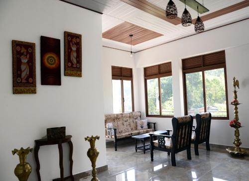 een woonkamer met een tafel, stoelen en ramen bij Green Bird Villas in Kandy