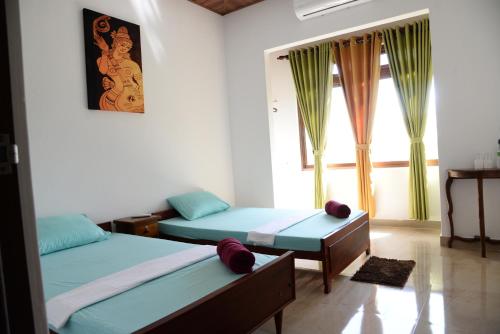 een kamer met 2 bedden en een raam bij Green Bird Villas in Kandy