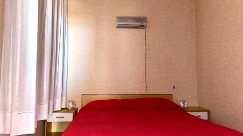 ein Schlafzimmer mit einem roten Bett und einem Fenster in der Unterkunft SE068 - Senigallia, bilocale sul mare al residence Piramidi in Scapezzano