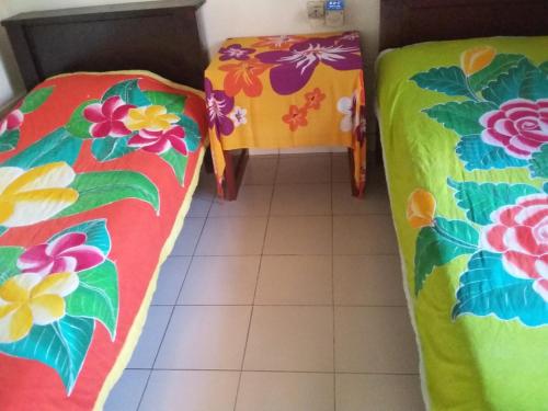 two beds in a room with a tiled floor at Dika Accommodation Ubud in Ubud