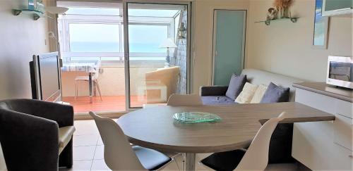 ein Wohnzimmer mit einem Tisch und Stühlen sowie eine Küche in der Unterkunft Bel appartement rénové VUE PANORAMIQUE SUR MER à PERROS-GUIREC - ref 822 in Perros-Guirec