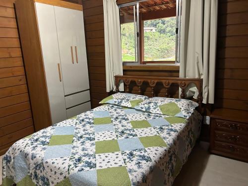 ドミンゴス・マルチンスにあるChalé Essência do Valeのベッドルーム1室(青と緑のキルトのベッド1台付)