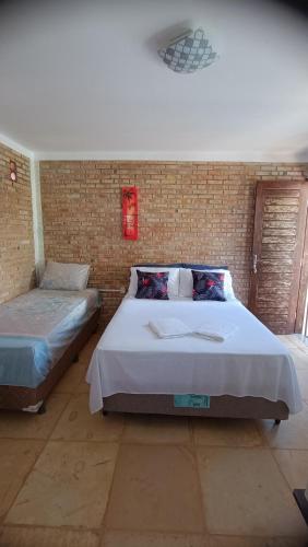 a bedroom with two beds and a brick wall at Pousada Preguiça in Canoa Quebrada