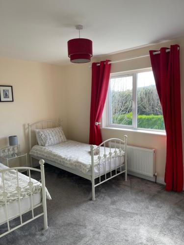 a bedroom with two beds and a window with red curtains at Glor Na Farraige 15 in Knights Town