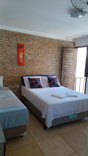 a bedroom with two beds and a brick wall at Pousada Preguiça in Canoa Quebrada