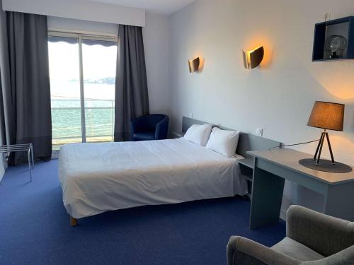 une chambre d'hôtel avec un lit, un bureau et une fenêtre dans l'établissement Superbe appartement TRES BELLE VUE MER à PERROS-GUIREC - Réf 824, à Perros-Guirec
