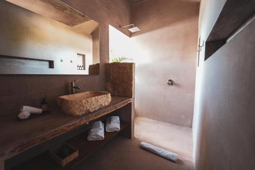 a bathroom with a stone sink and a shower at Nikau Hotel El Cuyo - Adults Only in El Cuyo