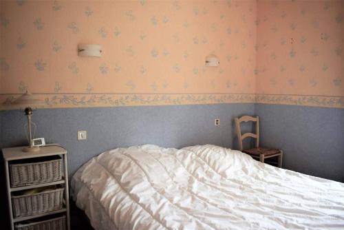 um quarto com uma cama branca e uma cadeira em Appartement 2 chambres avec superbe vue mer sur la plage de Trestrignel à PERROS-GUIREC - Réf 834 em Perros-Guirec