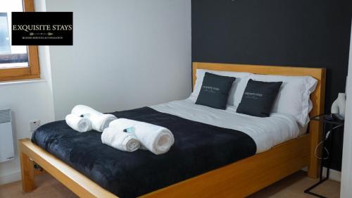 a bed with rolled towels on top of it at Exquisite, 2 bed apartment with free parking! in Coventry