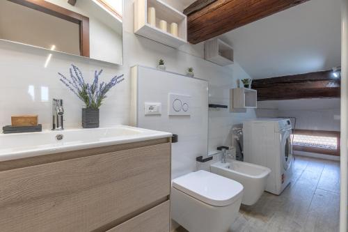 a white bathroom with a toilet and a sink at Coperta Retreat! Near Estense Castle in Ferrara