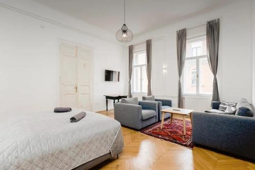 um quarto com uma cama, 2 cadeiras e uma mesa em BudapeStayz - Izabella Studios em Budapeste