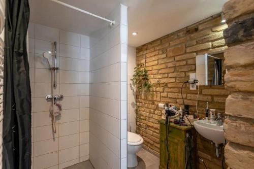 uma casa de banho com um WC, um lavatório e uma parede de pedra em BudapeStayz - Izabella Studios em Budapeste