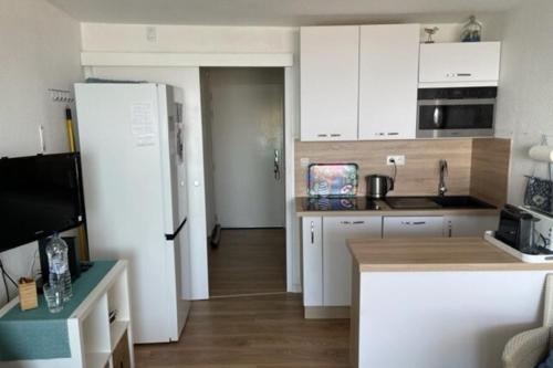 une cuisine avec des armoires blanches et un réfrigérateur blanc dans l'établissement Elegance sea view with swimming pool, à Frontignan