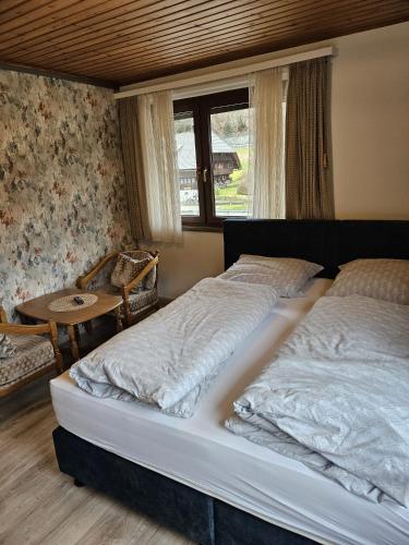 a bedroom with two beds and a table and a window at Am Wehrastrand App 2 in Todtmoos